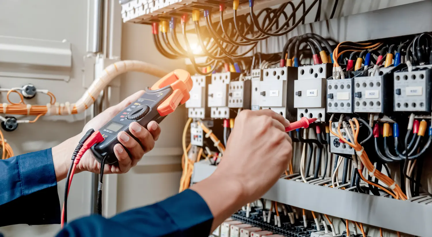 Ein Elektriker verwendet ein Multimeter, um die elektrische Installation und den Stromleitungsstrom in einem Schaltschrank einer elektrischen Anlage zu testen.